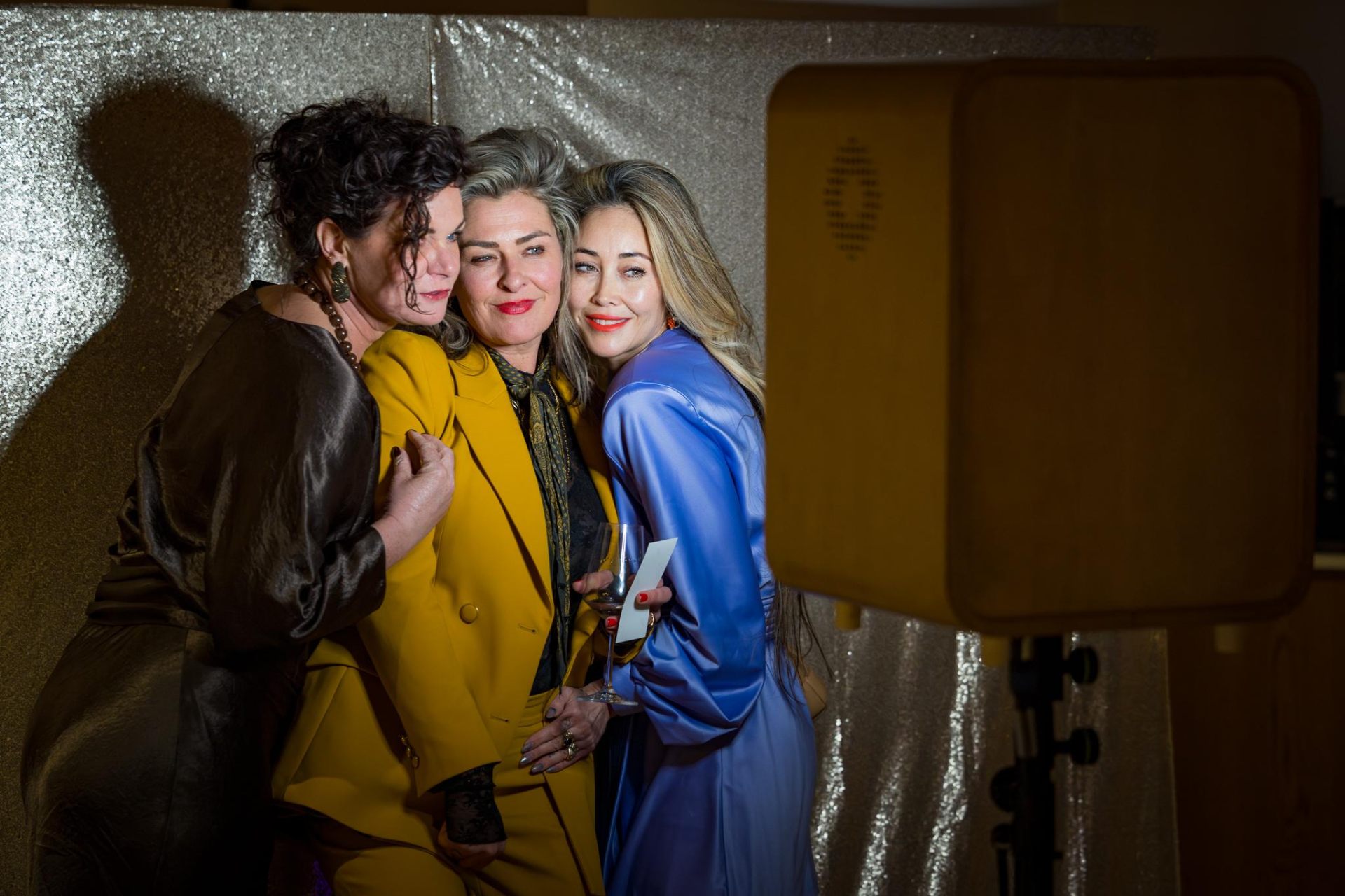 Drie dames bij photobooth met glittergordijn